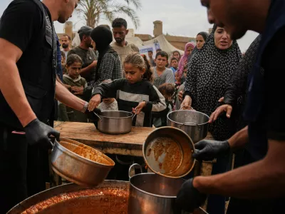 Palestinians receive food donated by the World Food Programme at a displacement camp in Deir al-Balah, in the central Gaza Strip, Sunday, Oct. 18, 2026. (AP Photo/Abdel Kareem Hana)