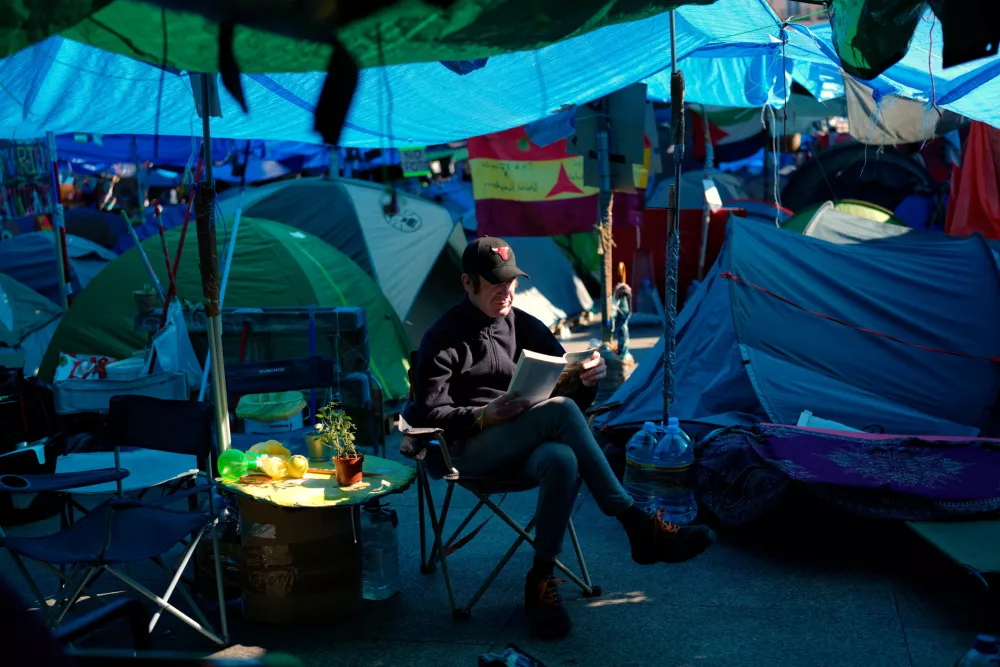 A man reads a book at a makeshift camp set up by protesters in Madrid's Puerta del Sol square, demanding stronger laws to protect renters, Monday, Oct. 26, 2026. (AP Photo/Bernat Armangue) / Foto: Bernat Armangue