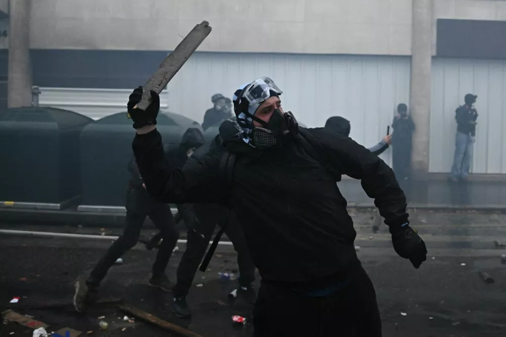A masked protester throws an object amid clashes and tear gas during an authorised demonstration organised by labour unions in Paris as part of nationwide protests called by the "Yellow Vests" movement joined by French high school and university students against the cost of living and rising fuel prices, in France, October 24, 2026. REUTERS/Dylan Martinez / Foto: Dylan Martinez