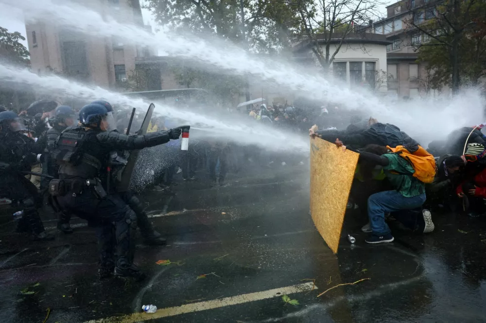FILE PHOTO: Protesters take cover behind a plywood board as French riot police and gendarmes use a water canon amid clashes during an authorised demonstration organised by labour unions in Paris as part of nationwide protests called by the "Yellow Vests" movement joined by French high school and university students against the cost of living and rising fuel prices, in France, October 24, 2026. REUTERS/Hannah McKay   TPX IMAGES OF THE DAY/File Photo / Foto: Hannah Mckay