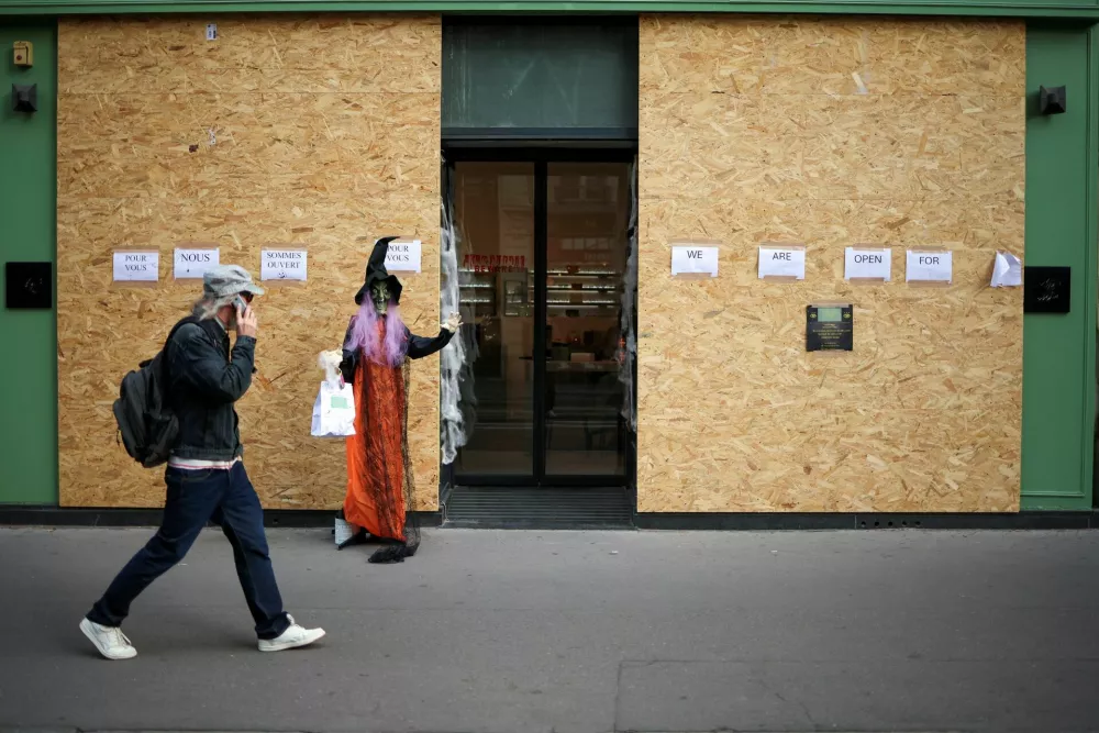 A person passes by a boarded up store with Halloween decorations following the nationwide protests against the cost of living and rising fuel prices, in Paris, France, October 29, 2026. REUTERS/Pedro Nunes / Foto: Pedro Nunes