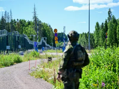 An officer from a special unit of the Finnish Border Guard stands in front of the border fence at a closed border crossing on the Finnish-Russian border.