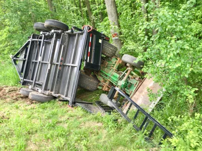 Overturned tractor and trailer laying in the ditch after an accident