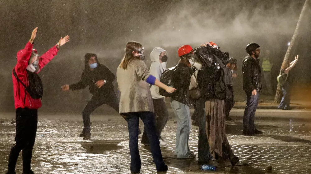 Anti-government protesters stand amid the spray from a police water canon in Tirana, Albania, late Tuesday, Oct. 20, 2026. (AP Photo/Boris Grdanoski)