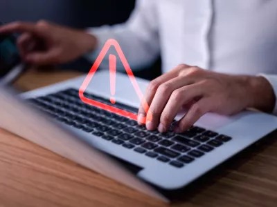 Error and maintenance concept. Businessman or it staff, programmer, developer using computer laptop with triangle caution warning sign for notification.