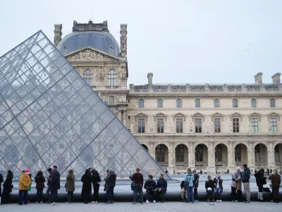 Ljudje čakajo pred muzejem Louvre. 