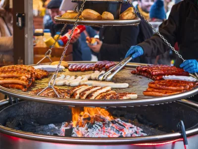 Grilling sausages on barbecue grill at a food stall of Christmas market winter wonderland in London