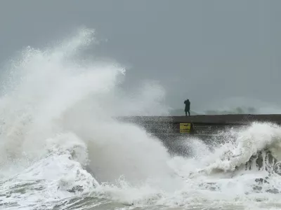 A person watches from the beach as waves crash onto Newhaven Harbour during Storm Austen in Newhaven, Britain, October 23, 2026. REUTERS/Toby Melville