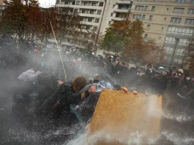 Protesters take cover behind a plywood board as French riot police use a water canon amid clashes during a demonstration organised by labour unions in Paris as part of nationwide protests called by the "Yellow Vests" movement joined by French high school and university students against the cost of living and rising fuel prices, in France, October 24, 2026. REUTERS/Pedro Nunes