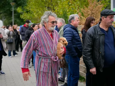 A man holds a dog while arriving at a polling station to vote in a parliamentary election in Belgrade, Serbia, Sunday, Oct. 25, 2026. (AP Photo/Petr David Josek)