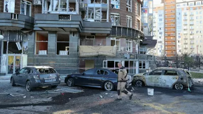 A man walks past damaged cars outside a residential complex hit by what local authorities described as a Ukrainian overnight drone strike, amid the Russia-Ukraine conflict, in central Belgorod, Russia, October 25, 2026. REUTERS/Stringer