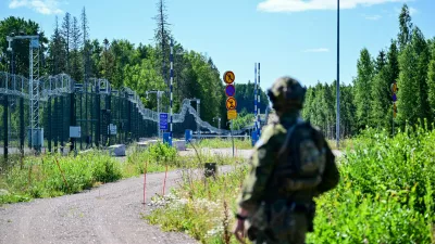 An officer from a special unit of the Finnish Border Guard stands in front of the border fence at a closed border crossing on the Finnish-Russian border. / Foto: Sebastian Christoph Gollnow