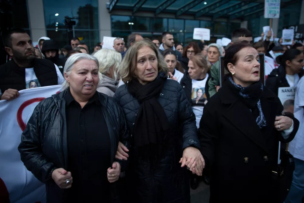 Family members of Arlinda Zekaj hold hands during a protest in Pristina, Kosovo, as thousands gather to condemn the killing of the Kosovo-American woman, whose death sparked public outrage and renewed calls for accountability over violence against women, on Wednesday, Oct. 28, 2026. (AP Photo/Visar Kryeziu)