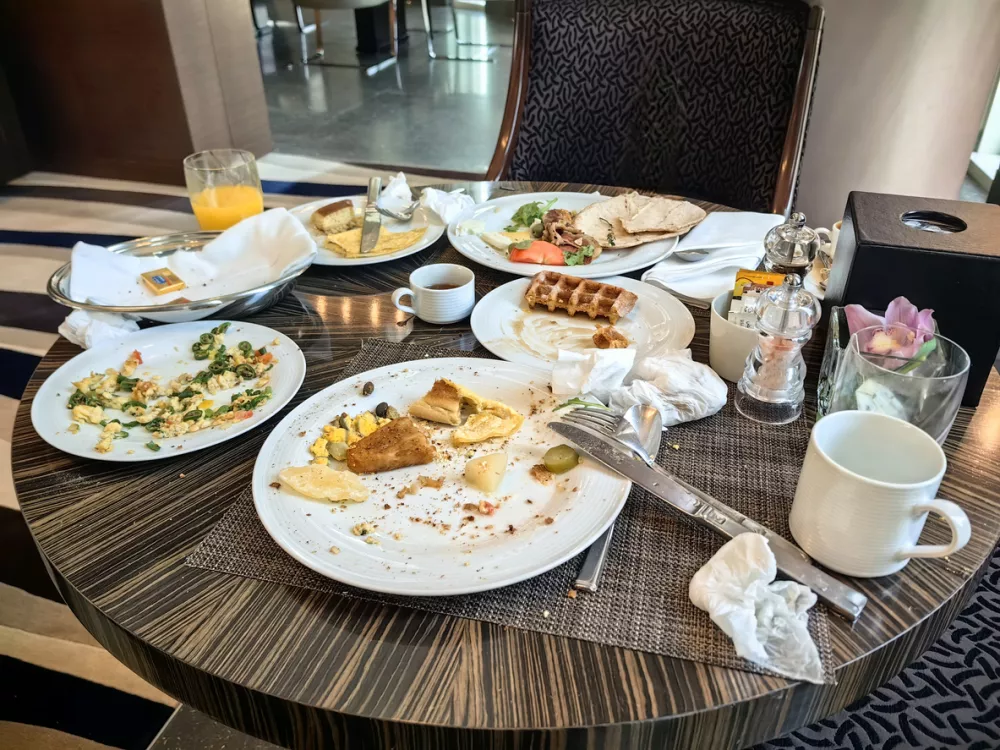 The condition of the dining table was dirty and messy after breakfast, with leftover food on the plates and scattered utensils.