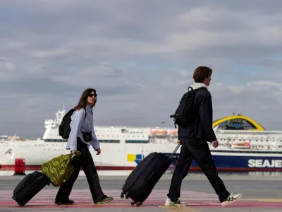 Passengers walk through the port of Piraeus during a 24-hour seafarers' strike over pay, working conditions and safety, alongside protests by port workers against the transport of military equipment through ports, near Athens, Greece, Friday, Oct. 30, 2026. (AP Photo/Thanassis Stavrakis)