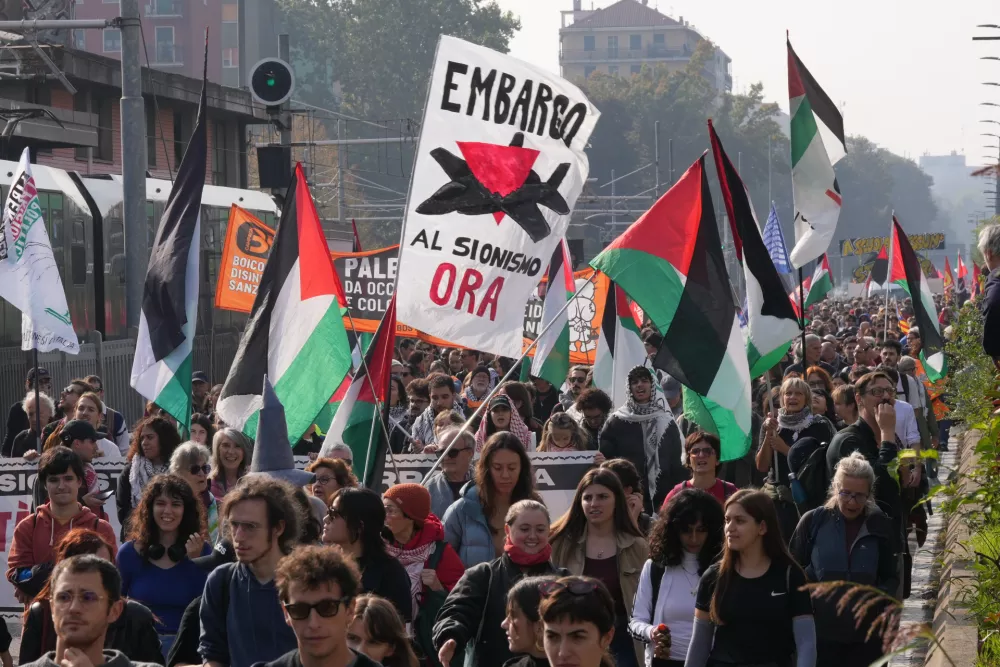 Demonstrators wave Palestinian flags and carry a banner reading "Embargo Zionism Now" during a nationwide general strike called by grassroots unions to protest rising living costs, low wages and military spending in Milan, Italy, Friday, Oct. 30, 2026. (AP Photo/Antonio Calanni)