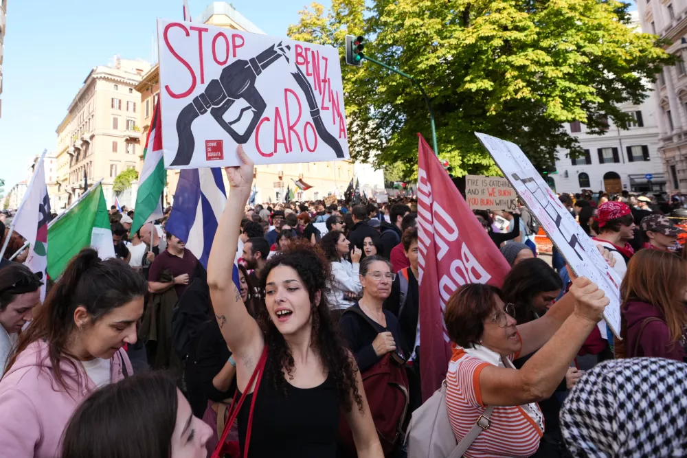 A demonstrator holds a placard reading "Stop Benzina Caro," protesting high gasoline prices, during a nationwide general strike called by grassroots unions to protest rising living costs, low wages and military spending in Rome, Friday, Oct. 30, 2026. (AP Photo/Alessandra Tarantino)