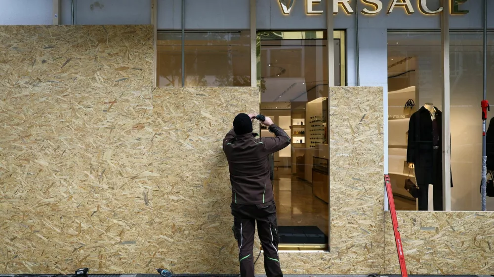 A worker secures a fashion store with wooden boards ahead of expected protests by the youth movement "Gen Z regelt" in Frankfurt, Germany, October 30, 2026. REUTERS/Kai Pfaffenbach