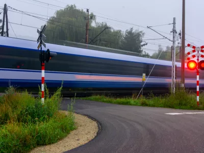 Passenger train passes railway crossing with red warning light, long exposure, motion blur, rail transport, safety, railway infrastructure, travel.