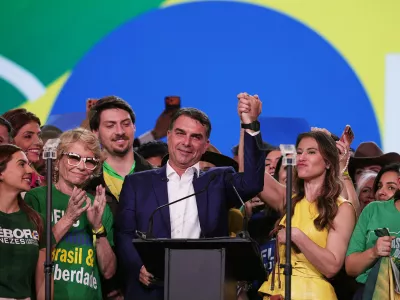 Brazilian Sen. Flavio Bolsonaro, flanked by his mother Rog&eacute;ria Bolsonaro, second left, and wife Fernanda, acknowledges supporters during the Liberal Party convention where he was confirmed as the party's presidential candidate,in Sao Paulo, Saturday, July 25, 2026. (AP Photo/Ettore Chiereguini)