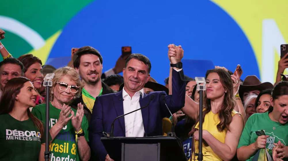 Brazilian Sen. Flavio Bolsonaro, flanked by his mother Rog&eacute;ria Bolsonaro, second left, and wife Fernanda, acknowledges supporters during the Liberal Party convention where he was confirmed as the party's presidential candidate,in Sao Paulo, Saturday, July 25, 2026. (AP Photo/Ettore Chiereguini)