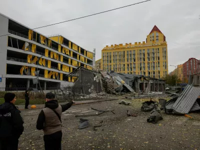 Residents and a police officer stand at the site of a residential area hit by a late evening Russian missile strike, amid Russia's attack on Ukraine in Kyiv, Ukraine October 30, 2026. REUTERS/Valentyn Ogirenko