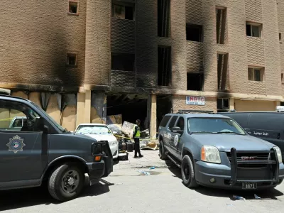 A Kuwaiti police officer is seen in front of a burnt building following a deadly fire, in Mangaf, southern Kuwait, June 12, 2024. REUTERS/Stringer