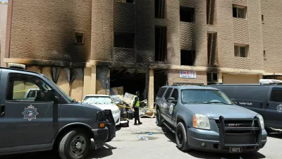 A Kuwaiti police officer is seen in front of a burnt building following a deadly fire, in Mangaf, southern Kuwait, June 12, 2024. REUTERS/Stringer