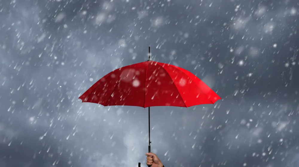 Red umbrella in the hands of businessmen amid a rainstorm.