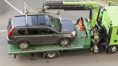 ﻿Moscow, Russia - May 22, 2019: Tow truck lifting the Nissan car for improper parking. Image can be used for topics like traffic offense, travel, traffic laws, traffic rules, iniquity, lawlessness, infringement of rights, business, help