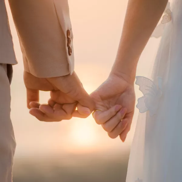 The bride and groom use the little finger together. lovely couple hold hand with sunset background