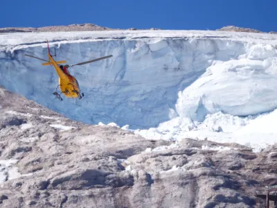 A helicopter participates in a search and rescue operation over the site of a deadly collapse of parts of a mountain glacier in the Italian Alps amid record temperatures, at Marmolada ridge, Italy July 6, 2022. REUTERS/Guglielmo Mangiapane ?