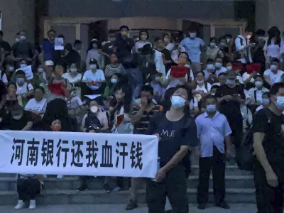 People hold banners and chant slogans stage a protest at the entrance to a branch of China's central bank in Zhengzhou in central China's Henan Province on July 10, 2022. A large crowd of angry Chinese bank depositors faced off with police Sunday, some reportedly injured as they were roughly taken away, in a case that has drawn attention because of earlier attempts to use a COVID-19 tracking app to prevent them from mobilising. (AP Photo)