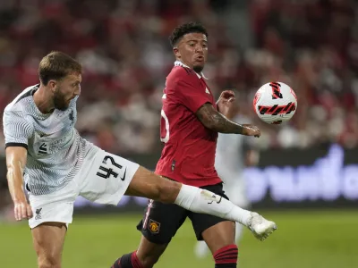 Liverpool's Nat Philips, left, fights for the ball with Manchester United's Jadon Sancho during their pre-season soccer match at Rajamangala national stadium in Bangkok, Tuesday, July 12, 2022. Manchester United beat Liverpool 4-0.(AP Photo/Sakchai Lalit)