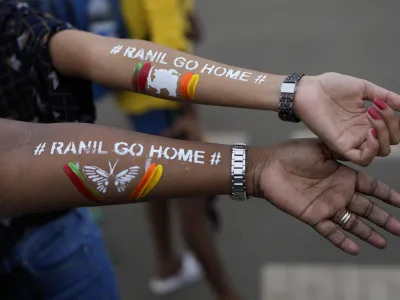 Girls display their arms painted with message "Ranil go home' referring to Prime Minister Ranil Wickremesinghe at the protest site in Colombo, Sri Lanka, July 17, 2022. (AP Photo/Rafiq Maqbool)