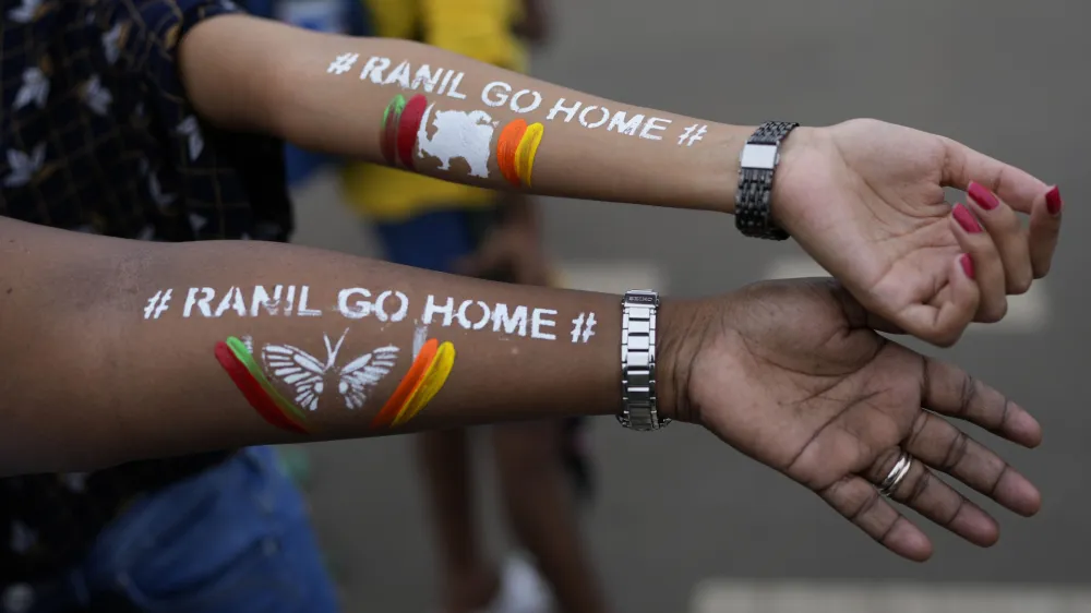 Girls display their arms painted with message "Ranil go home' referring to Prime Minister Ranil Wickremesinghe at the protest site in Colombo, Sri Lanka, July 17, 2022. (AP Photo/Rafiq Maqbool)