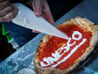 Neapolitan 'pizzaiuoli' (pizza makers) celebrate UNESCO's recognition by offering slices of pizza to passers-by on the street in Naples, Italy, Thursday, Dec. 7, 2017. UNESCO on Thursday added the art of the Neapolitan pizza maker to its list of "intangible cultural heritage of humanity." (Cesare Abbate /ANSA via AP)