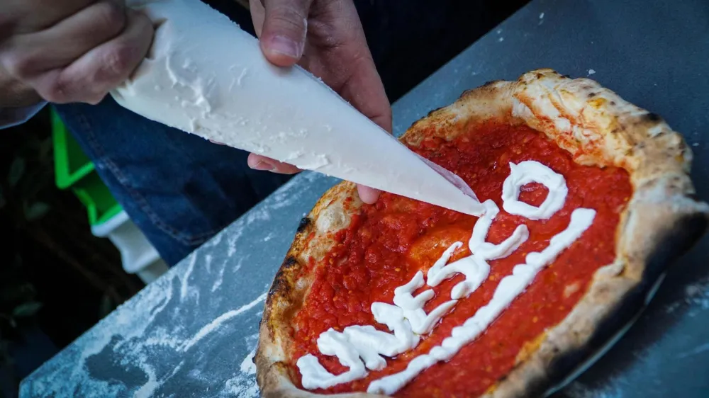 Neapolitan 'pizzaiuoli' (pizza makers) celebrate UNESCO's recognition by offering slices of pizza to passers-by on the street in Naples, Italy, Thursday, Dec. 7, 2017. UNESCO on Thursday added the art of the Neapolitan pizza maker to its list of "intangible cultural heritage of humanity." (Cesare Abbate /ANSA via AP)