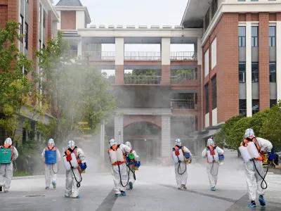 Workers in protective suits disinfect the compound of a primary school before schools reopen for the upcoming semester, following the coronavirus disease (COVID-19) outbreak in Wuhan, Hubei province, China August 25, 2021. China Daily via REUTERS ATTENTION EDITORS - THIS IMAGE WAS PROVIDED BY A THIRD PARTY. CHINA OUT.