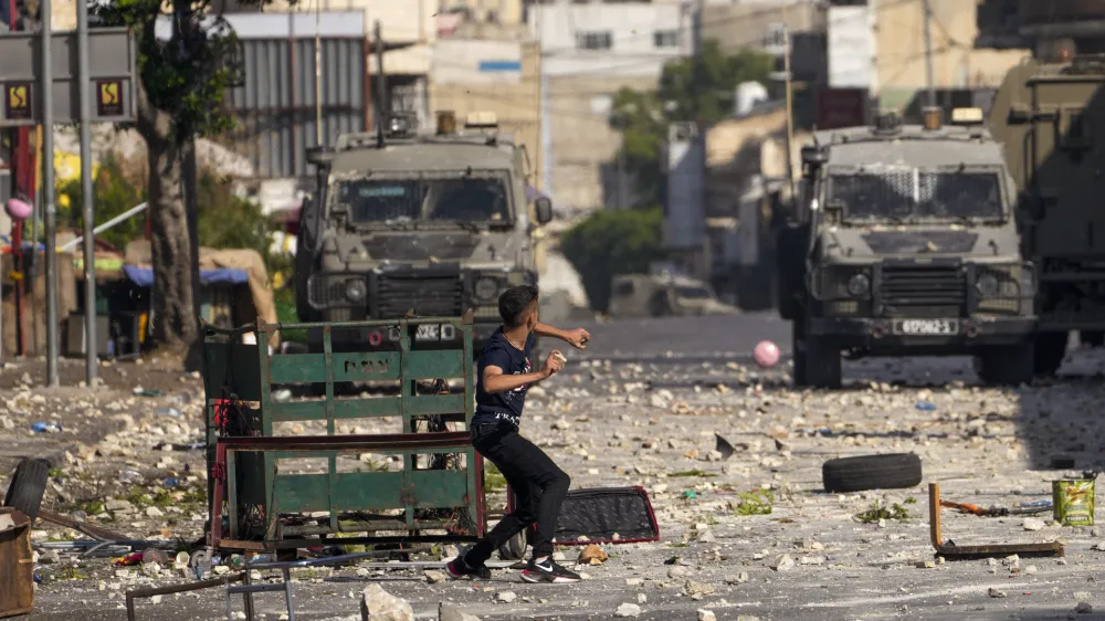 Palestinian demonstrators clash with the Israeli army while forces carry out an operation in the West Bank town of Nablus, Tuesday, Aug. 9, 2022. Israeli police said forces encircled the home of Ibrahim al-Nabulsi, who they say was wanted for a string of shootings in the West Bank earlier this year. They said al-Nabulsi and another Palestinian militant were killed in a shootout at the scene, and that troops found arms and explosives in his home. (AP Photo/Majdi Mohammed)