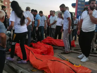 Emergency workers and people gather the bodies of people who were killed in a traffic accident in Derik, southern Turkey, Saturday, Aug. 20, 2022. Two major traffic accidents in southern Turkey left at least 35 people dead, officials said late Saturday. The latest incident in Derik, Mardin province, occurred when the brakes of an articulated truck failed, causing it to crash into two other vehicles near a gas station. (Kubra Nur Atik/IHA via AP)