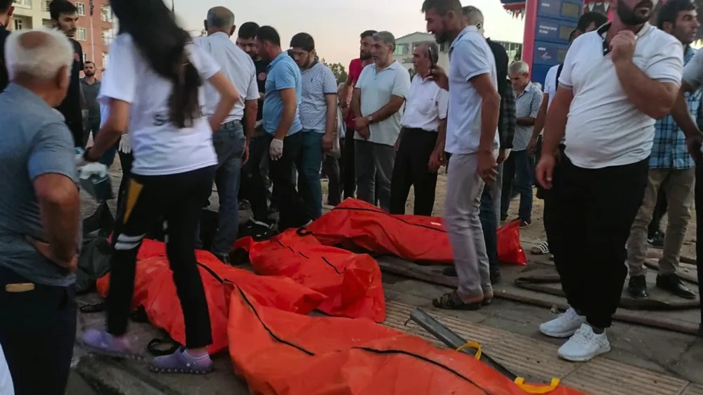 Emergency workers and people gather the bodies of people who were killed in a traffic accident in Derik, southern Turkey, Saturday, Aug. 20, 2022. Two major traffic accidents in southern Turkey left at least 35 people dead, officials said late Saturday. The latest incident in Derik, Mardin province, occurred when the brakes of an articulated truck failed, causing it to crash into two other vehicles near a gas station. (Kubra Nur Atik/IHA via AP)