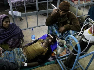 A patient is surrounded by relatives as he takes oxygen and saline while being treated in a hospital after drinking toxic alcohol in Diamond Harbour, near Kolkata, India, Thursday, Dec. 15, 2011. A tainted batch of bootleg liquor has killed scores and sent dozens more to the hospital in villages outside Kolkata, officials said. (AP Photo/Bikas Das)