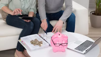 ﻿Close-up Of Couple Sitting On Sofa Calculating Bills At Home