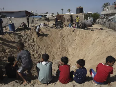 Palestinian children sit at the edge of a crater after an Israeli airstrike in Khan Younis, southern Gaza Strip, Friday, June 21, 2024. (AP Photo /Jehad Alshrafi)