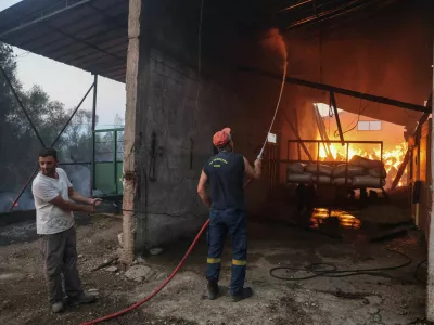 A firefighter works to extinguish the flames in a burning building as a wildfire burns in the village of Kalfas, in southern Greece, June 21, 2024. REUTERS/Giorgos Moutafis