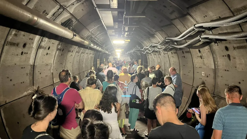 HANDOUT - 23 August 2022, ---: A handout image with permission from Kate Scott's Twitter shows passengers in an emergency tunnel of the Eurotunnel between France and England. After one of the trains broke down, passengers in the tunnel had to leave their carriages and were escorted through the emergency tunnel on foot. Photo: Kate Scott/Twitter/PA Media/dpa - ACHTUNG: Nur zur redaktionellen Verwendung.