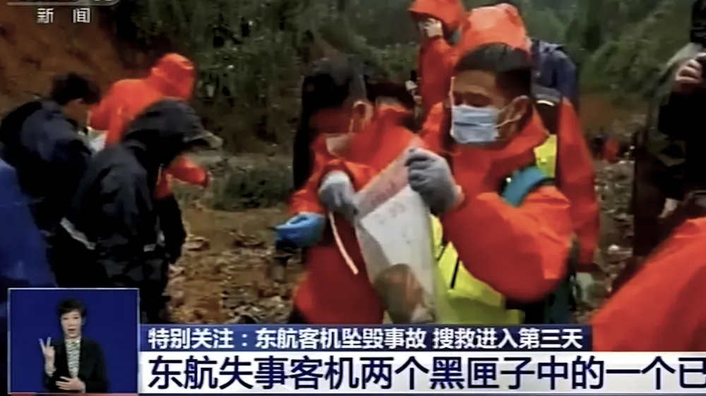 In this image taken from video footage run by China's CCTV, an emergency worker puts an orange-colored "black box" recorder into a plastic bag at the China Eastern flight crash site Wednesday, March 23, 2022, in Tengxian County in southern China's Guangxi Zhuang Autonomous Region. A Chinese aviation official said Wednesday that one of the two "black box" recorders had been found in severely damaged condition, two days after a China Eastern flight crashed in southern China with 132 people on board. (CCTV via AP Video)