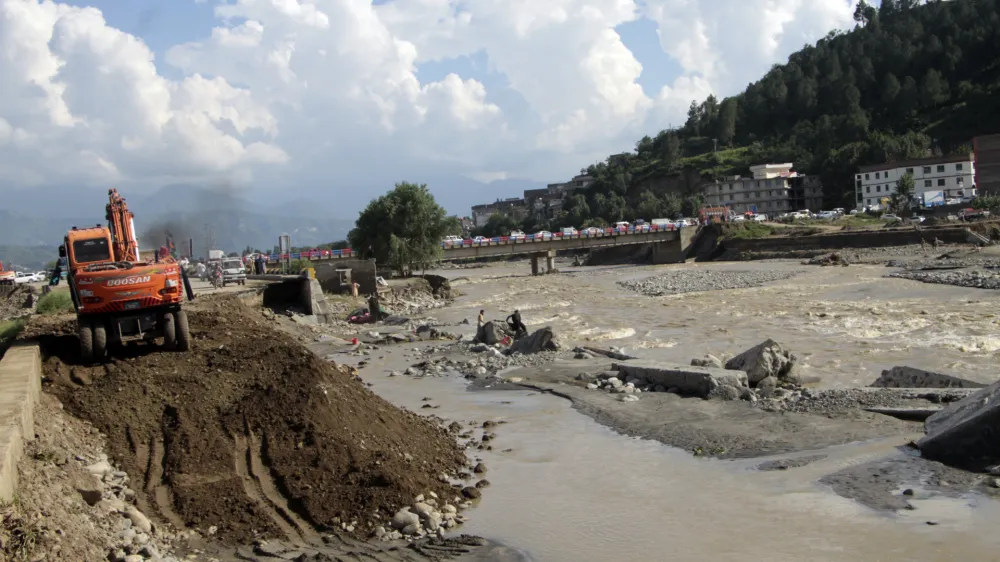 Local authorities use heavy machinery to rebuild a damaged road after a flood-affected area, in Swat valley, Pakistan, Sunday, Aug. 28, 2022. International aid for flood victims have started arriving in Pakistan, as military helicopters, troops and rescuers resumed operations early Monday to evacuate marooned people and deliver much-needed food after the deluge killed over 1,000 since mid-June. (AP Photo/Naveed Ali)