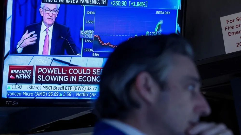 FILE PHOTO: A trader works, as Federal Reserve Chair Jerome Powell is seen delivering remarks on a screen, on the floor of the New York Stock Exchange (NYSE) in New York City, U.S. May 4, 2022. REUTERS/Brendan McDermid/File Photo